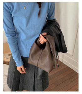 Détail d'un sac cabas en cuir marron foncé avec texture litchi porté par un mannequin