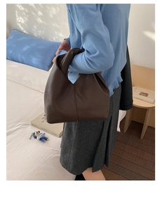 Détail de la texture cuir de lychee marron foncé sur un sac à main plissé élégant
