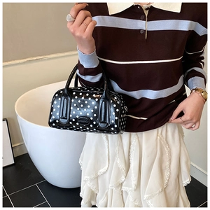 Detailed view of black polka dot handbag featuring a branded leather logo patch