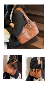 Detail van een bruine leren shopper met ritsen gepresenteerd door een model