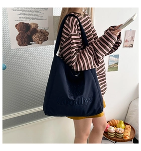 Detail of navy blue canvas tote bag with 3D embossed Never Say Goodbye lettering