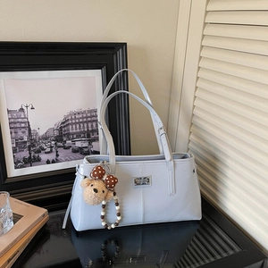 Detailed close-up of light blue tote bag with a cute bear charm and pearl chain accent