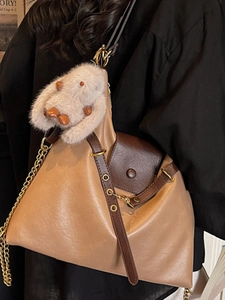 Vintage brown leather tote bag with chain strap and plush rabbit charm on model