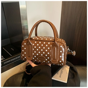 Detail view of brown polka dot boston bag with round handles and polished leather finish