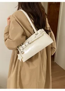 Sac à bandoulière en cuir crème avec breloque cœur porté par un mannequin en trench kaki