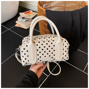 Detail of white Boston bag with black polka dots, featuring logo and detachable strap