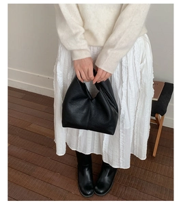 Détail d'un sac cabas en cuir grainé noir porté avec une tenue décontractée chic