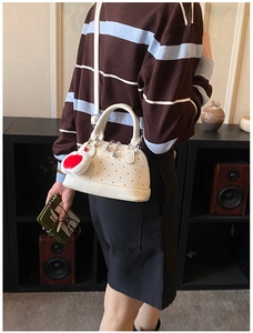Close-up of a white mini Boston bag with red polka dots and a heart plush keychain