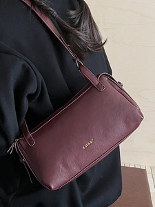 Minimalist vintage dark burgundy leather underarm bag with gold logo on black clothing