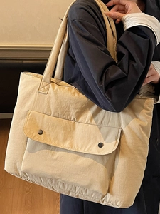 Minimalist beige oversized nylon tote bag with front flap pocket and metal buttons