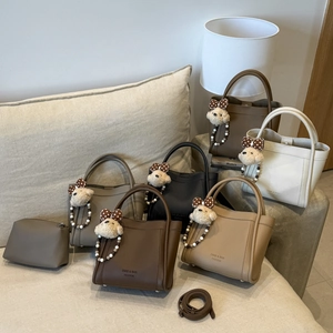 Detail of bucket bag showing lychee grain texture with cute bear charm and metal studs