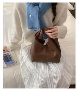 Détail d'un sac hobo en cuir marron foncé avec poignée nouée et texture de cuir grainé