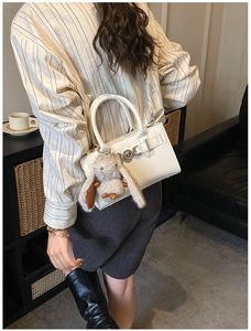 Détail du sac à bandoulière en cuir blanc avec breloque lapin en peluche sur un mannequin
