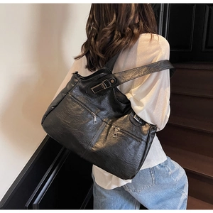 Detail showing the textured black faux leather tote with parallel silver zippers and wide strap