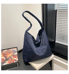 Detail of navy blue quilted tote bag featuring premium Never Say Goodbye embroidery