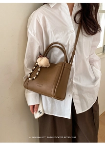 Detail of coffee brown lychee leather bucket bag with mushroom charm and beaded decor