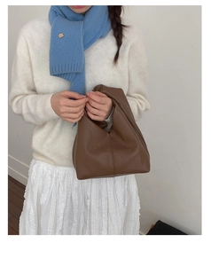 Gros plan du sac à main marron en cuir grainé avec un pull élégant en maille blanche