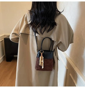 Detail of Korean-style mini bucket bag with two-tone suede finish on a trench coat model
