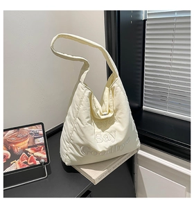 Detail of cream white puffer tote bag featuring Never Say Goodbye 3D embroidery text
