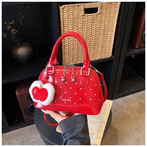 Detail of red polka dot handbag featuring a plush apple charm and metallic zipper