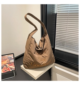 Detailed embroidery of Never Say Goodbye on a quilted brown nylon hobo shoulder bag