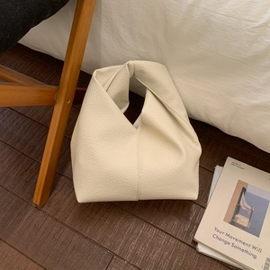 Détail du sac en cuir grainé crème avec une poignée nouée au design minimaliste moderne