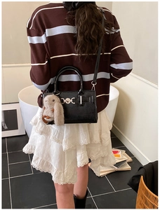 Détail du sac bandoulière en cuir brillant noir avec fermoir cœur et breloque lapin