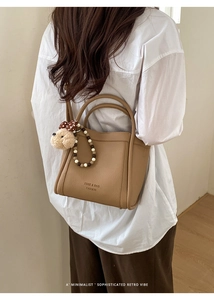 Detail of brown leather bucket bag with plush dog charm and wooden bead accessory