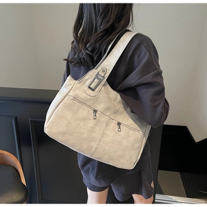Detail view of cream-white vintage tote bag featuring dual front zippers and wide shoulder strap