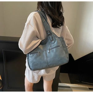 Detailopname van blauwe tote bag met dubbele ritszakken aan de voorkant en donker metalen beslag