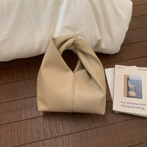 Vue détaillée du cuir grainé et de la poignée nouée sur le sac à main beige élégant