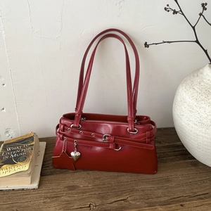 Détail du sac à bandoulière rouge vintage avec boucles argentées et breloques étoile