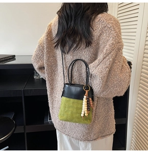 Detail of crossbody bucket bag with green quilted texture and beaded wood charms
