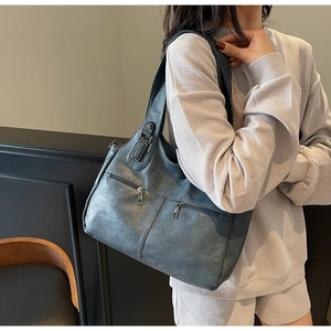 Close-up of a dark grey tote bag featuring pebble leather texture and dual front zippers
