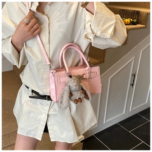 Sac bandoulière rose en cuir synthétique avec texture grainée et breloque lapin