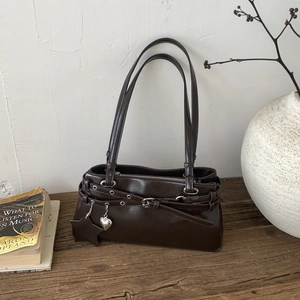 Détail du sac vintage en cuir marron avec des breloques et des accents métalliques