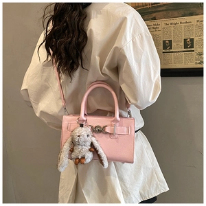 Détail du sac carré en cuir rose avec boucle métallique et pendentif lapin en peluche
