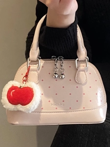 Pink polka dot handbag with gloss finish, red apple charm, and double zip closure