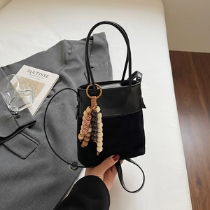 Detail of black bucket bag featuring mixed leather textures and colorful wooden bead charm