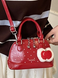 Cute red polka dot top-handle shell bag with a plush apple charm and shiny finish