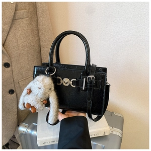 Détail du sac carré en cuir brillant noir avec boucle en cœur et breloque lapin en peluche
