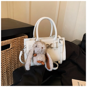 Détail d'un sac à main en cuir blanc avec fermoir argenté et charmant lapin en peluche