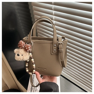 Detail of brown litchi pattern bucket bag with detachable strap and cute bear charm