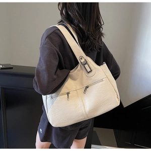 Close-up of off-white tote bag with litchi texture and gun-grey zipper pockets