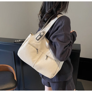 Close-up of cream leather tote bag with functional zippers and wide shoulder strap