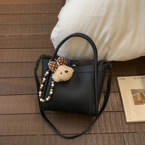 Detail of black lychee grain bucket bag with teddy bear charm and beaded strap