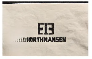 Close-up of black embroidered logo on white oxford fabric for durable travel backpack