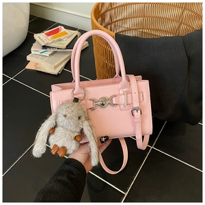 Détail du sac bandoulière en cuir verni rose avec boucle cœur et pendentif lapin en peluche