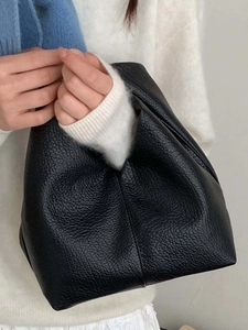 Sac à bandoulière minimaliste en cuir litchi noir porté par un mannequin en tenue décontractée