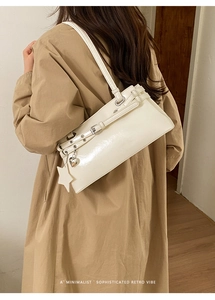 Gros plan d'un sac Boston blanc brillant avec breloque cœur et boucles métalliques